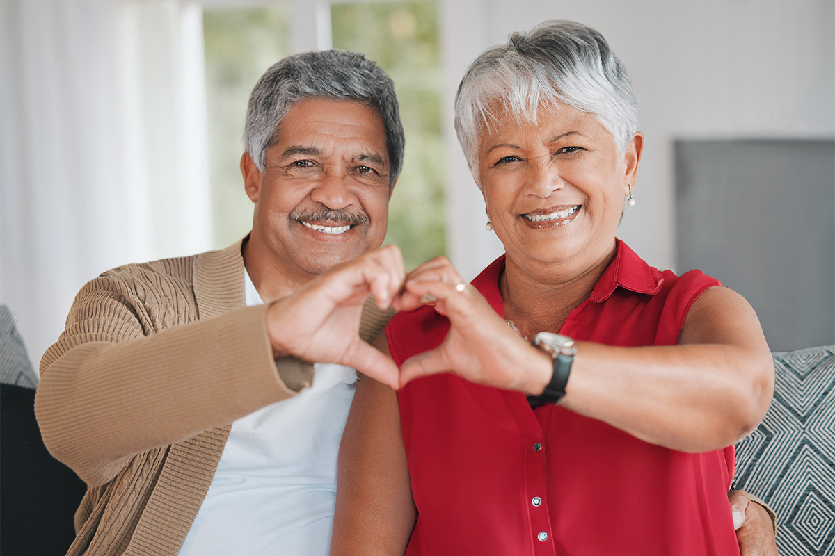 A man and a woman holding up their hands in the shape of a heart